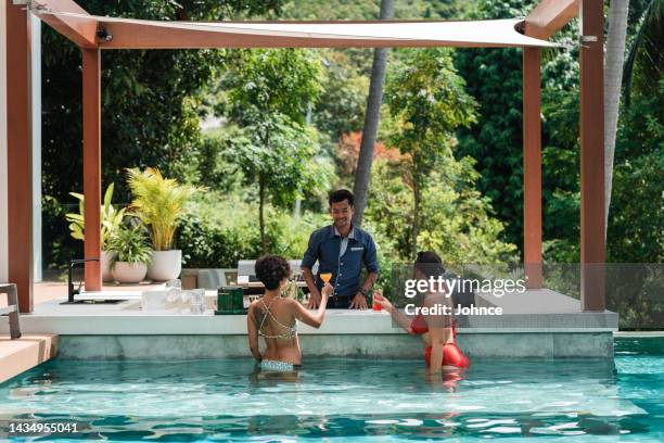 female friends enjoying coctails at a pool bar - poolside bar stock pictures, royalty-free photos & images