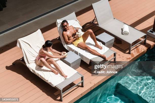 couple enjoying vacation by the pool - tanning bed stock pictures, royalty-free photos & images