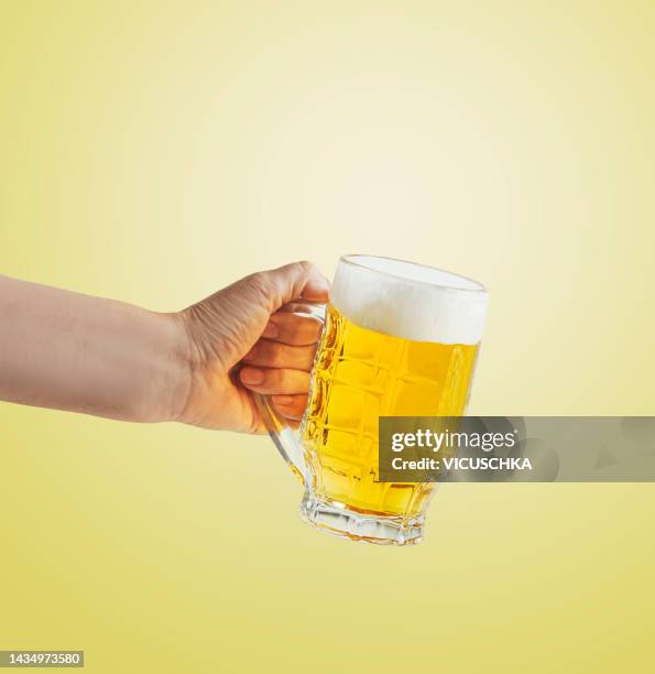 women hand holding beer mug with foam - beer glass hand stock pictures, royalty-free photos & images