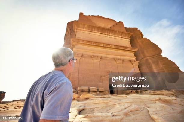 tourist admiring tomb of lihyan, son of kuza, in hegra - mada'in saleh stockfoto's en -beelden