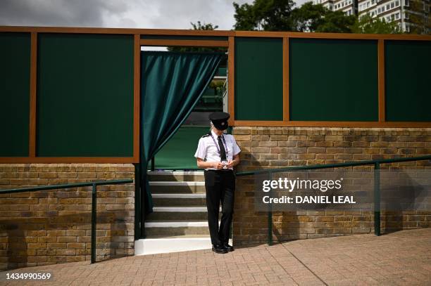 Security officer stands guard at the entrance of a court on the first day of the 2023 Wimbledon Championships at The All England Tennis Club in...
