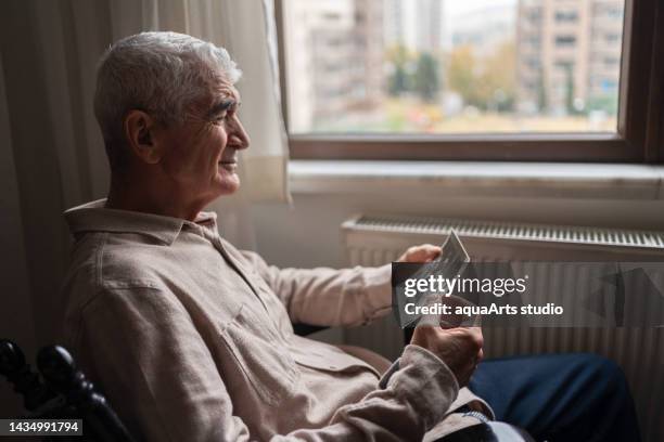 senior man looking at an old photo - widower stock pictures, royalty-free photos & images