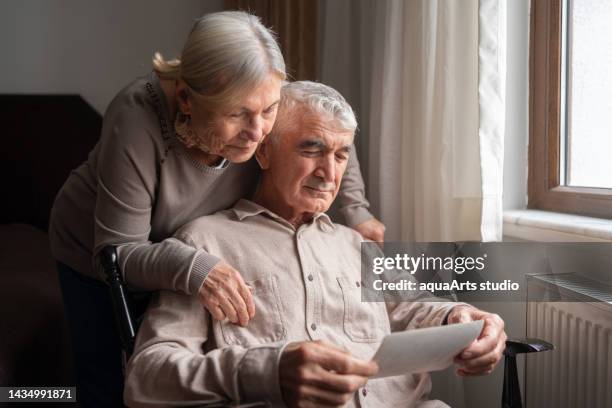 senior couple looking at an old photo - ziekte van alzheimer stockfoto's en -beelden