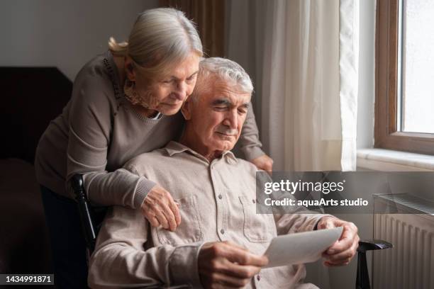 senior couple looking at an old photo - health history stock pictures, royalty-free photos & images