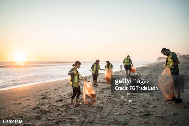 recicladores limpiando la playa - cleaning fotografías e imágenes de stock