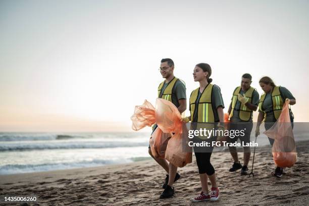 des recycleurs parlent en marchant sur la plage - volunteer beach photos et images de collection