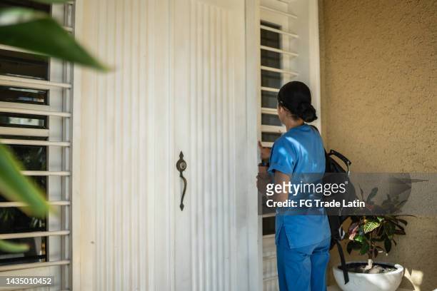 enfermera mediana de adultos presionando la campana mientras sostiene el café - door bell fotografías e imágenes de stock
