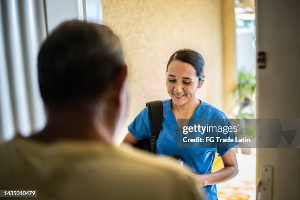 krankenschwester im mittleren erwachsenenalter kommt zu hause - client carer stock-fotos und bilder