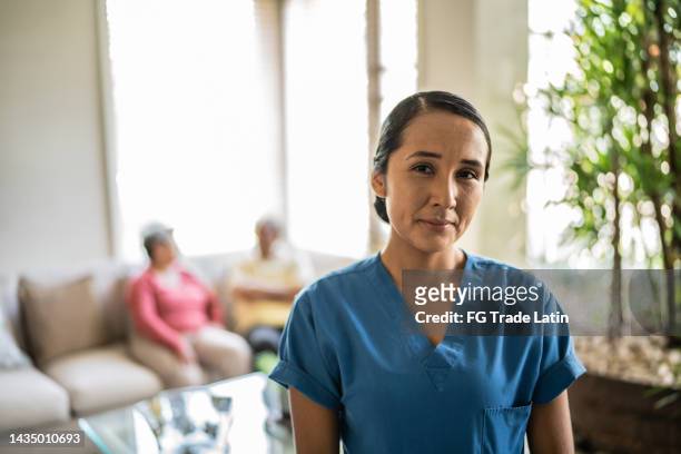 portrait of mid adult nurse in the living room at home - nursing assistant imagens e fotografias de stock