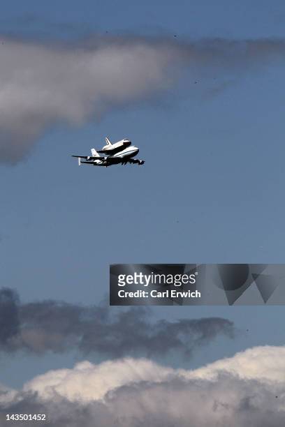 Space Shuttle Enterprise, mounted atop a 747 shuttle carrier aircraft, flies by prior to landing at John F. Kennedy International Airport on April...