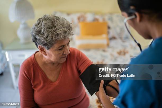 enfermera midiendo la presión de una mujer mayor en el dormitorio de un hogar de ancianos - pressure gauge fotografías e imágenes de stock