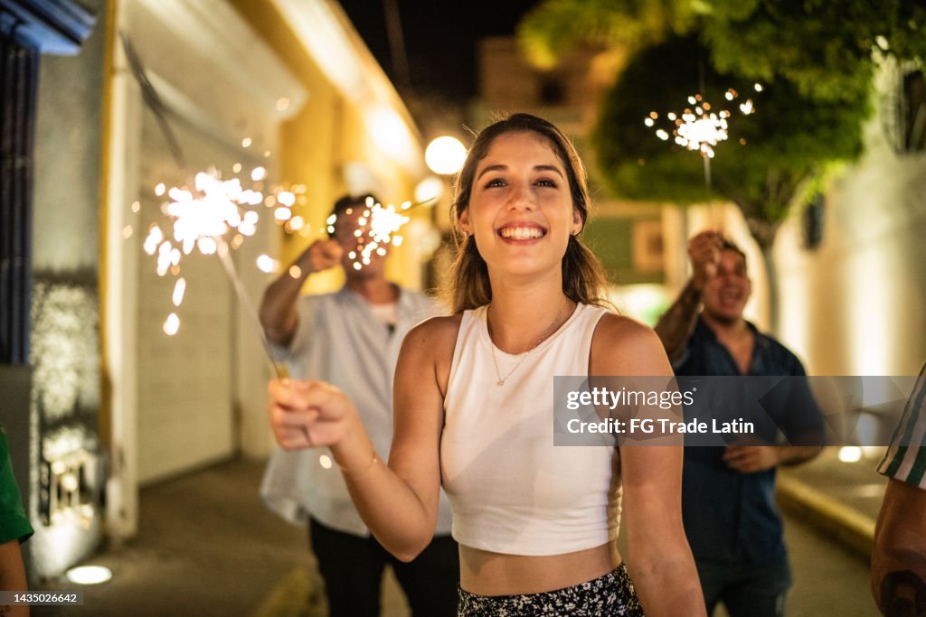 Giovane donna che gioca con scintille sulla strada di notte