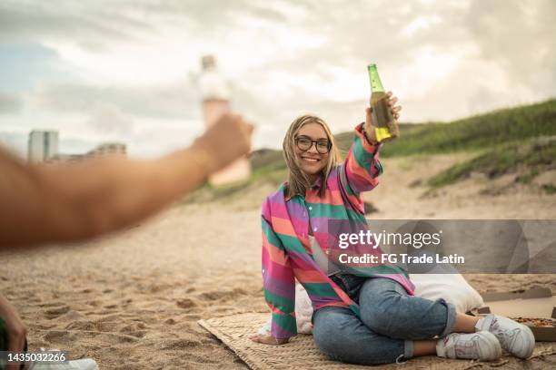 mujer joven haciendo un brindis de celebración en la playa - mexican picnic fotografías e imágenes de stock