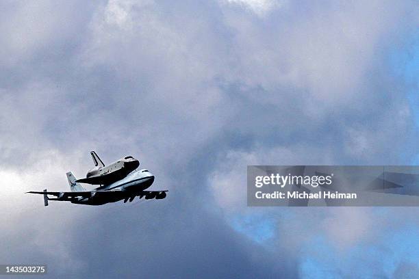 Space Shuttle Enterprise, mounted atop a 747 shuttle carrier aircraft, flies by prior to landing at John F. Kennedy International Airport on April...