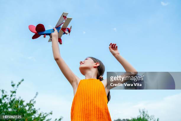 unrecognizable little girl playing with wooden airplane with imagination on summer daytime. - captains day stock-fotos und bilder