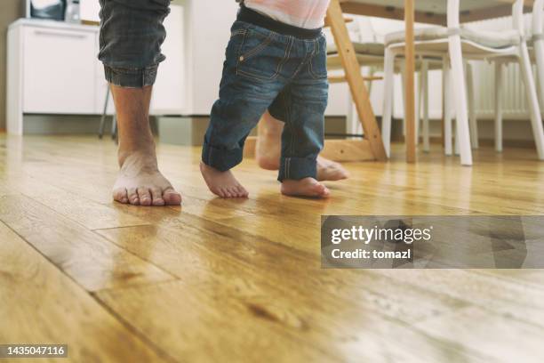 father teaching baby to walk - wooden floor low angle stock pictures, royalty-free photos & images