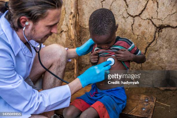 doutor que examina o menino africano novo na vila pequena, kenya - missionário - fotografias e filmes do acervo