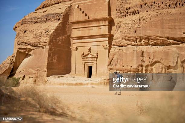 photographer working around sandstone rock-cut tombs, hegra - mada'in saleh stockfoto's en -beelden