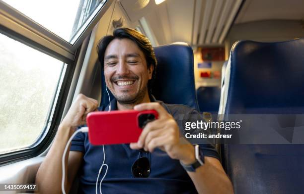 man riding on the train and watching a soccer game on his cell phone - travelgame stock pictures, royalty-free photos & images