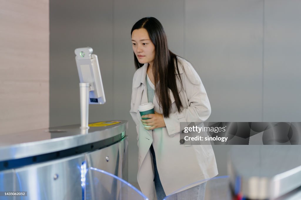 Asian lady is using face recognition system in modern office building