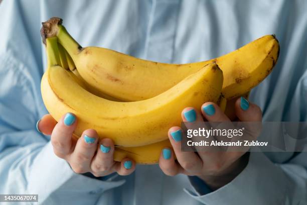 ripe yellow bananas in the hands of a woman, bought at a shopping market. the concept of vegetarianism, veganism and raw food. vegetarian, vegan food and diet. fruits, food background. retail sale of seasonal products. plant food, ethical consumption. - mature adult foto e immagini stock