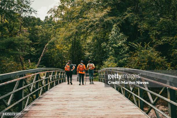 multigenerational women out for a hike crossing bridge - "marilyn nieves" stock pictures, royalty-free photos & images