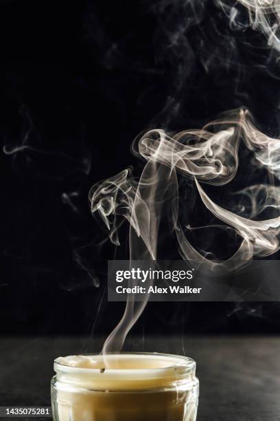 a ribbon of swirling smoke rising from a candle on back background - alex grey stock pictures, royalty-free photos & images