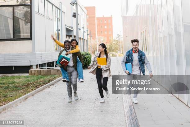 happy young adult group of college students running together outdoors at university campus after finishing classes - education concept - end of life stock pictures, royalty-free photos & images