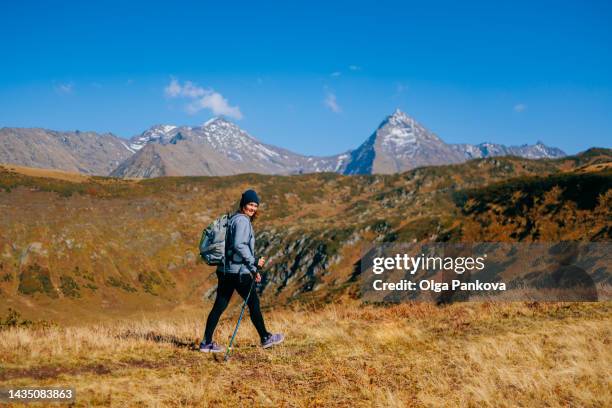 female tourist enjoys a hike with a picturesque mountain view in autumn. - hiking pole stockfoto's en -beelden