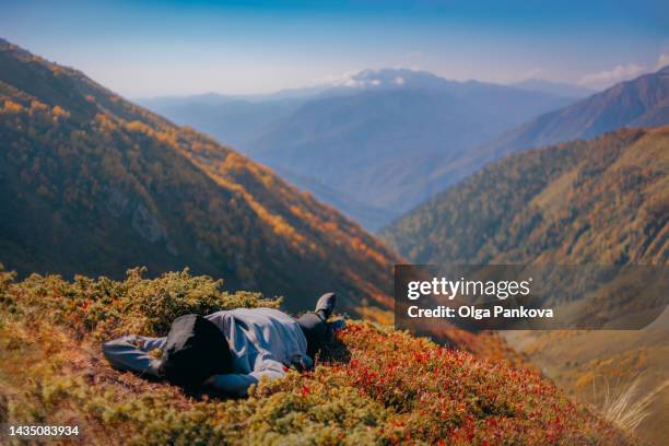 a female tourist enjoys lying down during an autumn mountain hike. - supino foto e immagini stock