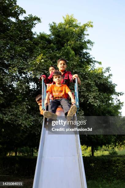 niños divirtiéndose en tobogán en el parque - área de juego fotografías e imágenes de stock