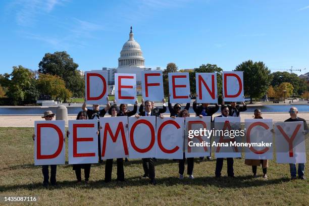 Activists hold up signs spelling out "Defend Democracy" during a protest to call on accountability for the January 6th attack on the U.S. Capitol...