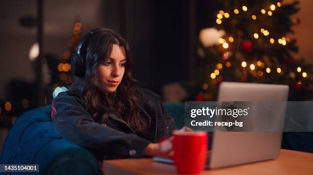 junge frau, die sich zu hause entspannt und zu weihnachten den laptop im wohnzimmer benutzt - büro bäume nacht stock-fotos und bilder