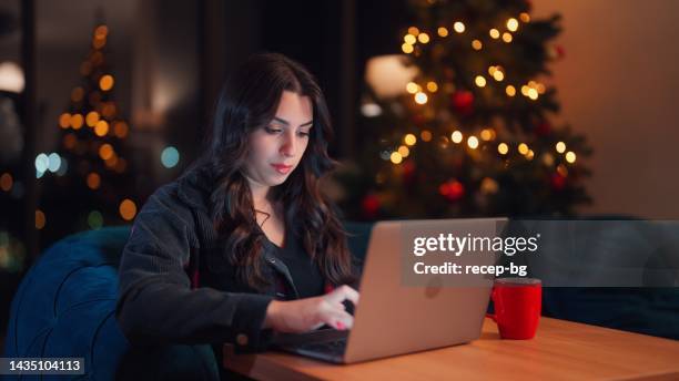 junge frau, die sich zu hause entspannt und zu weihnachten den laptop im wohnzimmer benutzt - büro bäume nacht stock-fotos und bilder