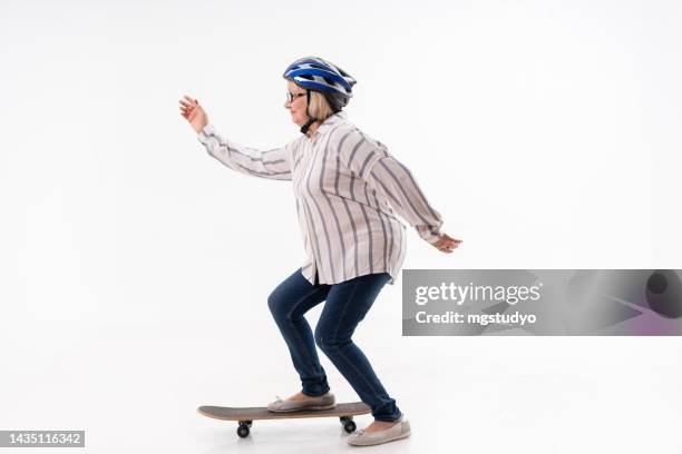 studio shot of a happy senior woman riding a skateboard - person skateboarding stock pictures, royalty-free photos & images