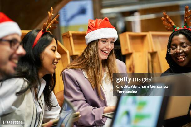 young people in the office looking at the laptop screen of one of the women and laughing - occupation hats stock pictures, royalty-free photos & images