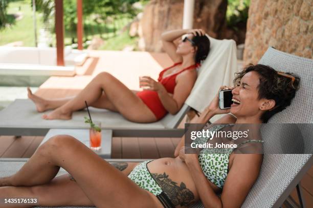 excited woman talking on the phone by the pool - woman excited sitting chair stock pictures, royalty-free photos & images