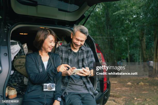 asian senior couple preparing gear for hike. - asian couple car stockfoto's en -beelden