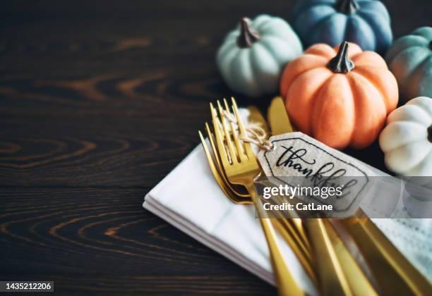 thanksgiving background with pumpkins and gold cutlery wrapped with a gift tag reading thankful - thanksgiving imagens e fotografias de stock