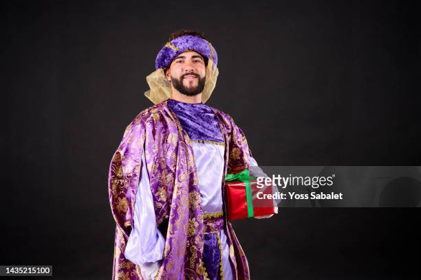 arabian king with gift box looking at camera - king royal person stock-fotos und bilder