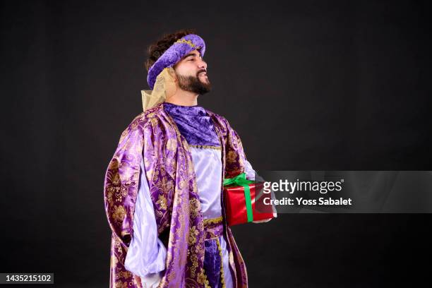 moorish king in purple suit with gift box - king royal person stock-fotos und bilder
