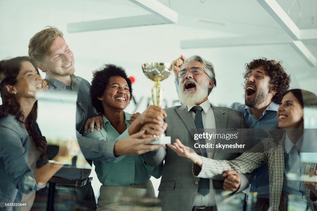 Cheerful business team celebrating winning a trophy in the office.