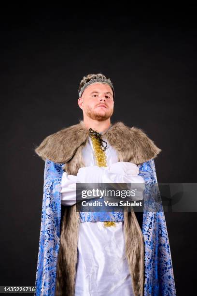 a young blond adult with a crown and dressed in a long cape looking at the camera - monarque rôle social photos et images de collection