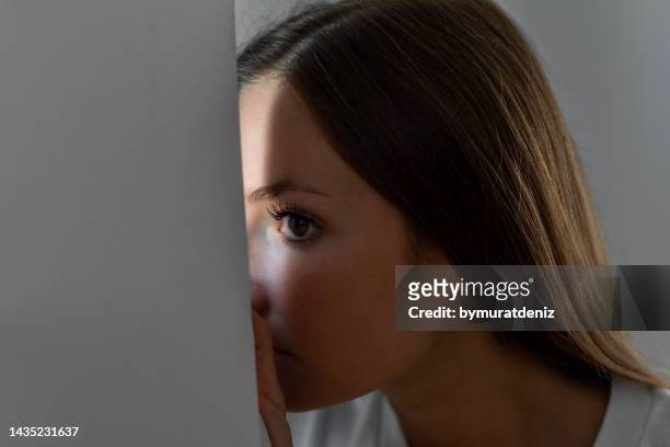 woman scared looking through the window seeking safety - stalker person stock pictures, royalty-free photos & images