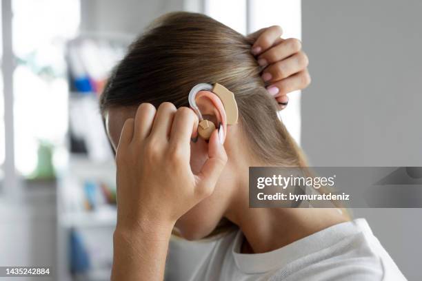 frau trägt ein hörgerät - deafness stock-fotos und bilder