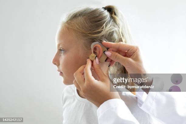 doctor putting an hearing aid in a child's ear - medical equipment stock pictures, royalty-free photos & images