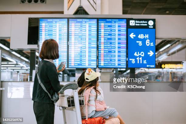 asiatische chinesische familie überprüft die boarding-zeit nach digitalem fahrplan - die neue normalität stock-fotos und bilder