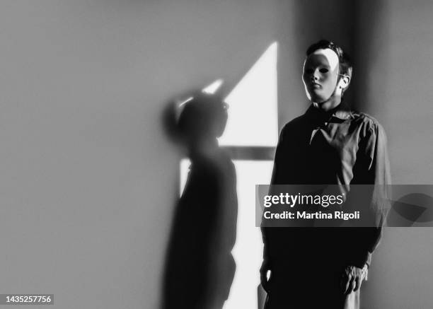 porträt eines jungen mannes mit maske und an der wand stehend mit schatten, schwarz-weiß - men costume black and white stock-fotos und bilder