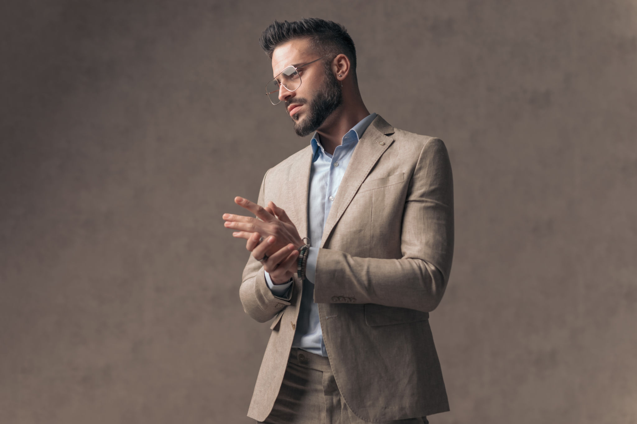 confident fashion man in elegant suit looking to side and rubbing palms confident fashion man in elegant suit looking to side and rubbing palms