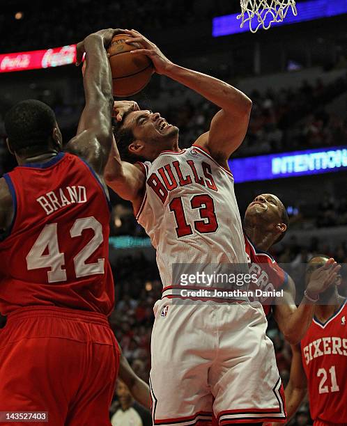 Joakim Noah of the Chicago Bulls is fouled by Evan Turner of the Philadelphia 76ers as Elton Brand gets his hand on the ball in Game One of the...